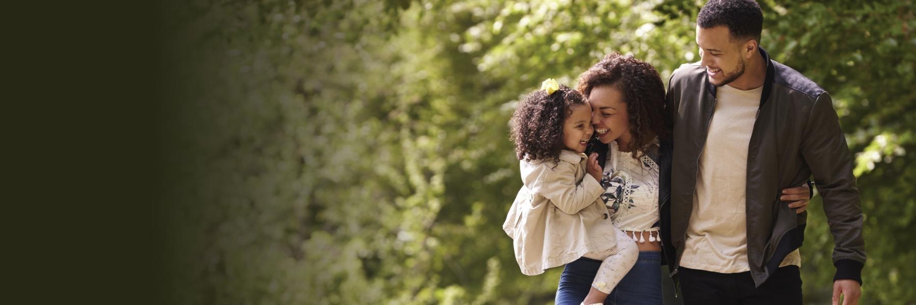 A happy family of three, including a mother, father, and young daughter.
